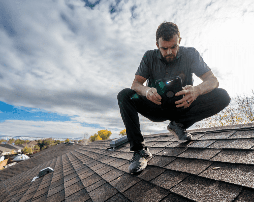 Man inspecting roof with smartphone