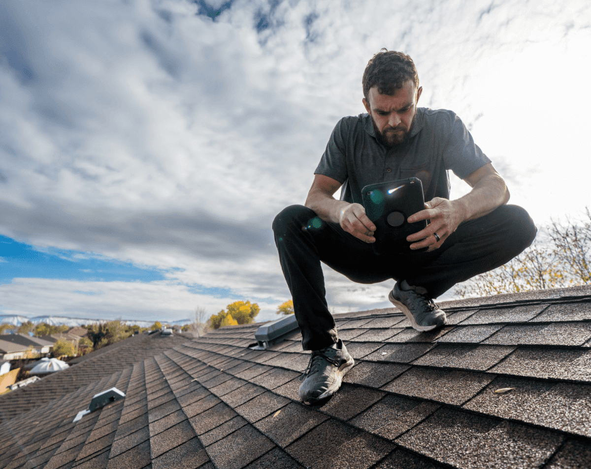 Man inspecting roof with smartphone