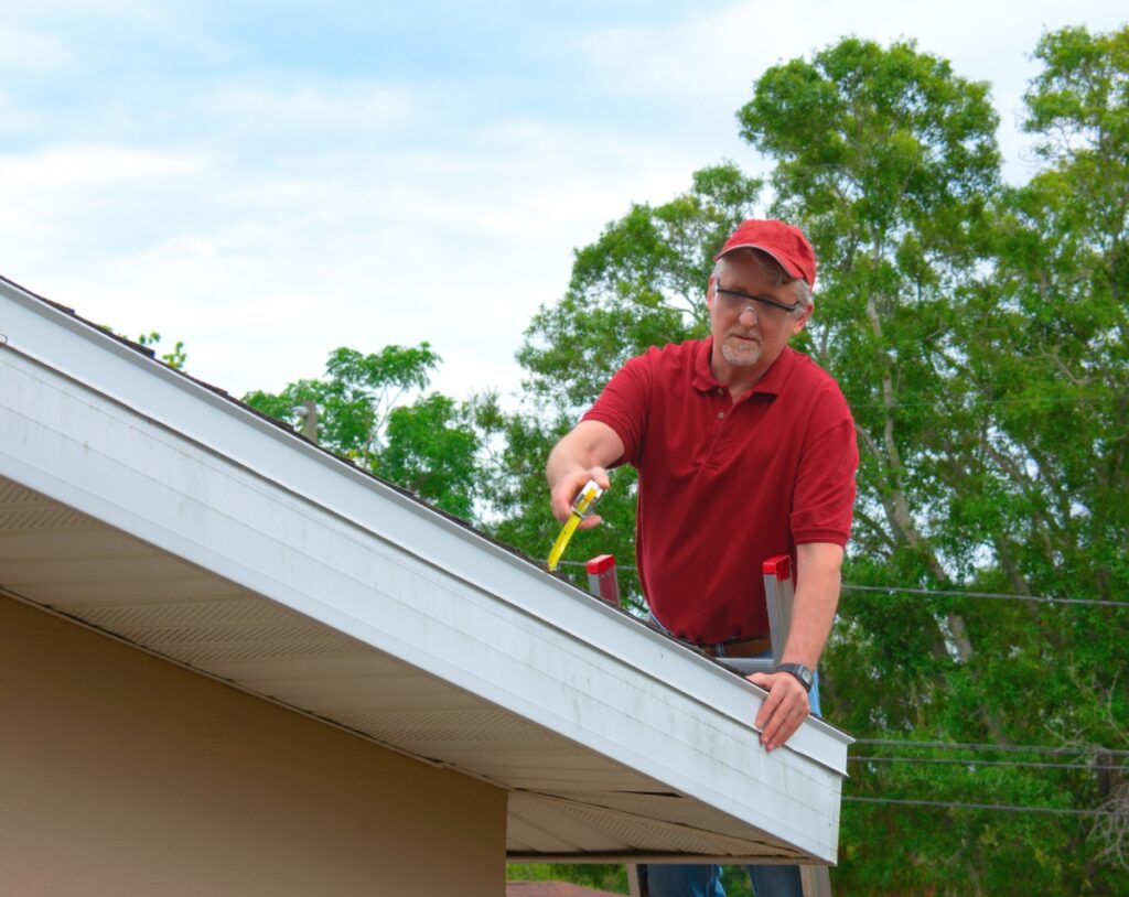Man cleaning gutters on a roof